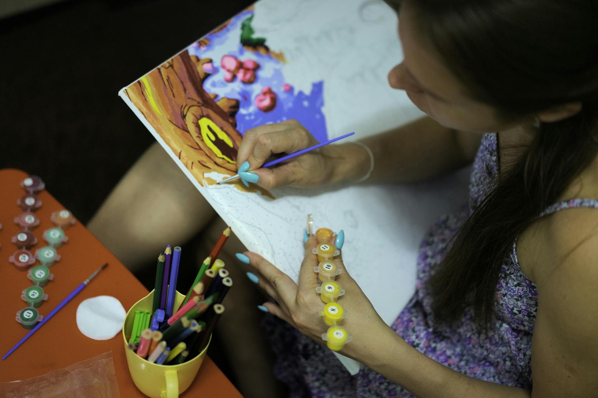 A woman engaged in creative painting with watercolors and brushes on canvas.