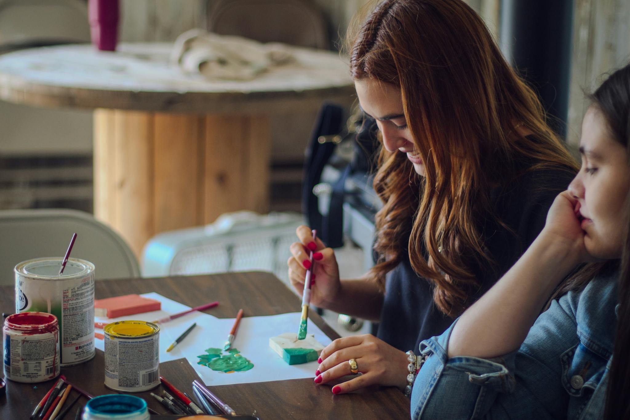 Two women engage in a creative painting activity, focused on art and expression.